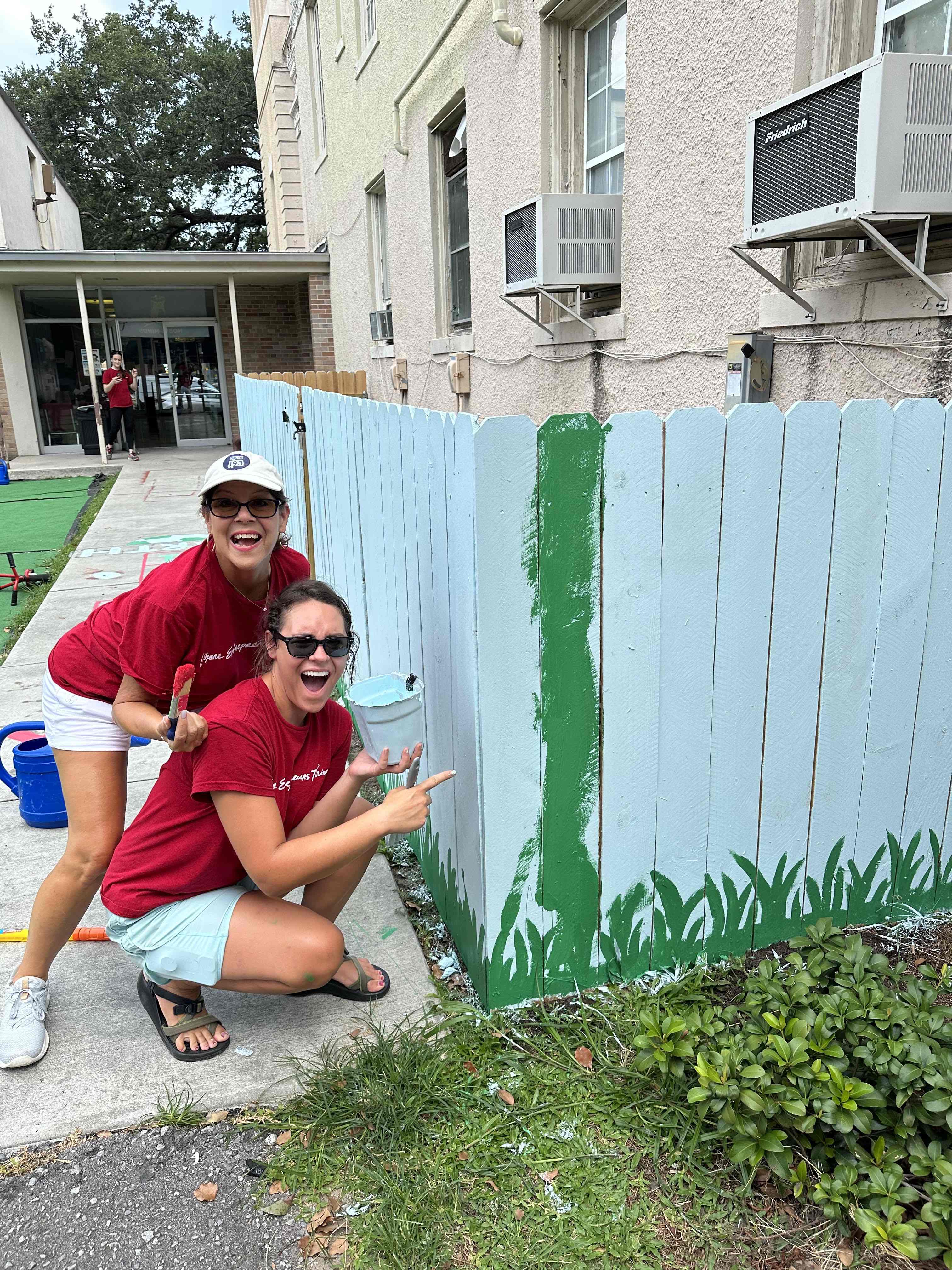 KWNO Shares volunteers painting a mural on a fence at a community building